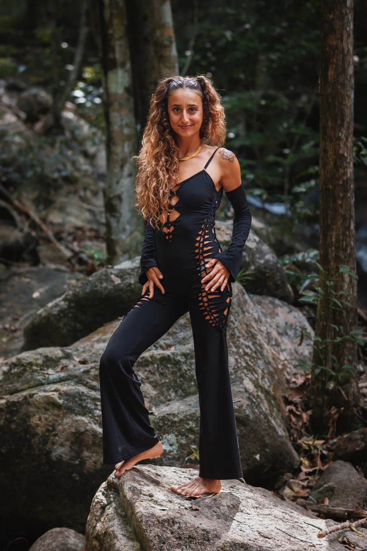 Soof standing barefoot among rocks and trees